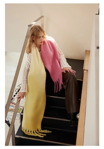 Detailed view of pink and yellow wool blend scarves with fringes on a model