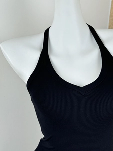 Close-up of black ribbed knit halter neck top with tight-fitting cut on white mannequin