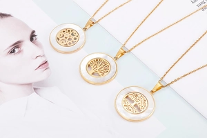 Detail of gold tree of life pendants with white shell inlay on stainless steel necklace