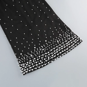 Vue détaillée de perles blanches en dégradé sur le tissu d'une robe noire bustier