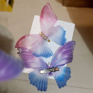Macro detail of gradient mesh butterfly hair clips with pearl and gold metal accents