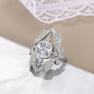 Close-up of crown ring with square gemstone and intricate silver filigree on marble