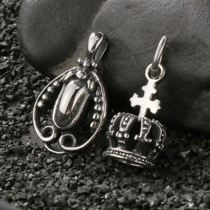 Vintage stainless steel cross crown and oval pendants on dark stone background