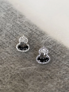 Close-up of silver gourd earrings with sparkling zircon crystals on grey velvet