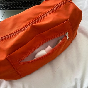 Bright orange waterproof nylon crossbody bag shown on white background with laptop