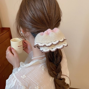 Detailed knit texture of a cream and pink crochet hair scrunchie on a low ponytail