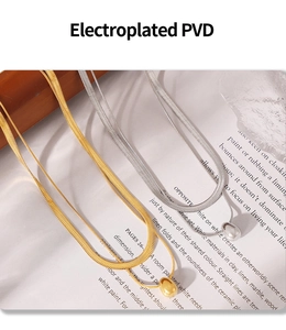 Detail of PVD gold and silver snake chain necklaces featuring oval pendants on a magazine