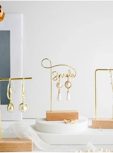 Detail of teardrop pearl earrings and gold ring on wooden jewelry display stand