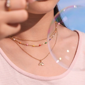 Collier doré multicouche avec perles colorées et pendentif nuage arc-en-ciel sur modèle