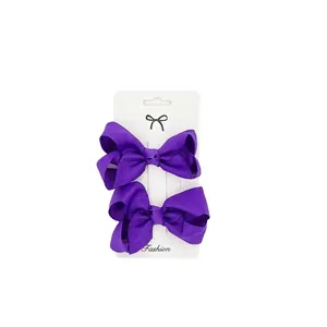Detail view of two purple ribbed ribbon bow hair clips on a white fashion display card