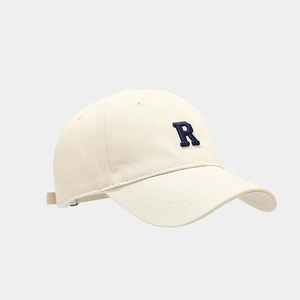 Close-up of cream baseball cap with navy blue R embroidery and classic curved brim