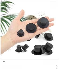 Hand holding various sizes of black plastic snowman top hats for DIY Christmas dolls