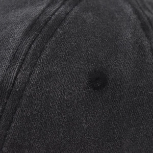 Détail macro d'une casquette en coton noir montrant les coutures et l'oeillet brodé