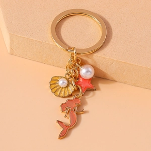 Detail of gold keychain with orange mermaid, yellow shell, red starfish, and white pearl charms