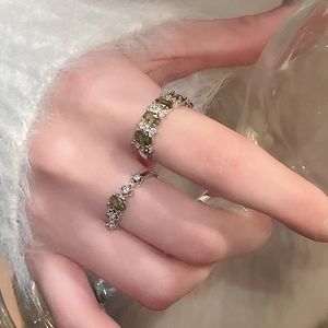 Detailed shot of two vintage silver rings featuring oval green stones and white crystals