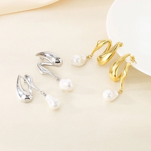 Detailed macro view of gold and silver irregular earrings with white baroque pearl pendants