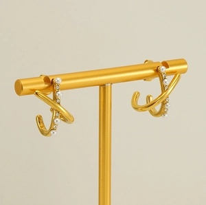 Close-up of gold-plated pearl earrings with sparkling zircons on a jewelry stand