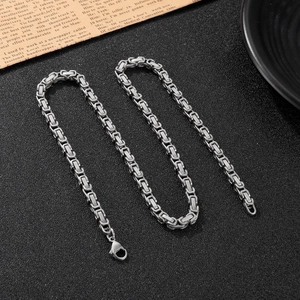 Men's stainless steel Byzantine chain necklace with lobster clasp on black textured surface