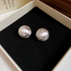 Detailed macro view of silver brushed spherical stud earrings with micro star-shaped accents