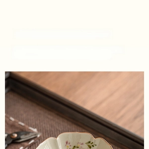 Macro view of hand-painted floral ceramic tea strainer with petal-shaped edges and porcelain filter