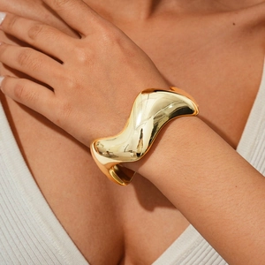 Close-up of polished gold wavy cuff bracelet with irregular geometric design