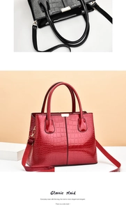 Detail of red and black patent leather handbag featuring stone texture and gold hardware