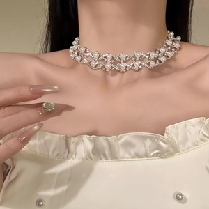 Close-up of pearl rhinestone necklace with silver mesh structure on a model