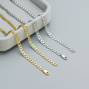 Detailed view of silver and gold Cuban link chains with lobster clasps on a jewelry tray