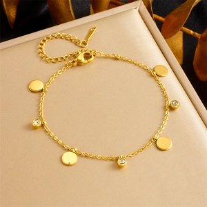 Detail van vergulde kettingarmband met gepolijste schijfjes en kralen met zirkoon