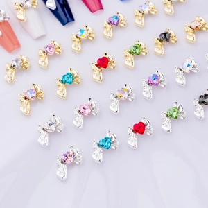 Detailed view of 3D bow nail charms with heart-shaped crystal rhinestones in various colors
