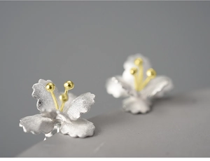 Macro detail of 925 silver flower stud earrings with gold stamen and matte petals