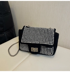 Close-up of sparkling silver rhinestones on black suede crossbody bag with chain