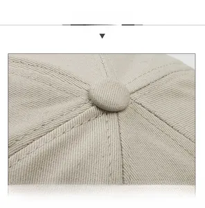 Detail view of cotton fabric stitching and top button on a beige retro docker hat