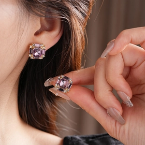 Detail of square purple stone earrings with gold border and white diamond accents