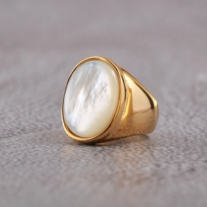 Dettaglio macro di anello in acciaio dorato con elegante inserto in conchiglia ovale
