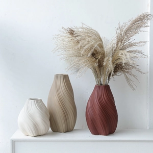 Tres jarrones minimalistas de cerámica con textura en espiral en beige, caqui y teja