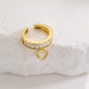 Golden heart charm ear cuff with sparkling zircon crystals on minimalist stone background