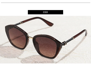 Detail view of large polygon tortoiseshell sunglasses with gold metal ring on temple
