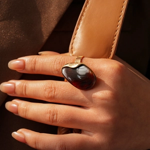 Gros plan d'une bague dorée ornée d'une grande pierre ovale marron sur fond de cuir