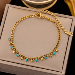 Macro view of gold stainless steel anklet with blue turquoise beads and gold ball charms