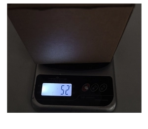 Close-up showing the pumpkin gnome ornament being weighed at 52 OZ on a digital scale