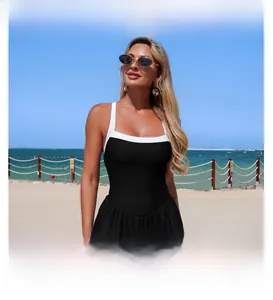 Classic black and white one-piece swimsuit featuring a skirted bottom on a sunny beach