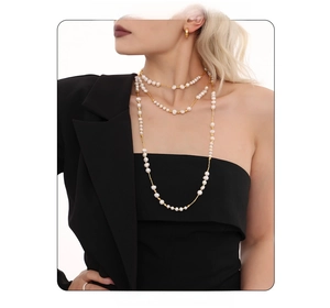 Detail of layered white pearl necklace with gold chain worn by a fashion model