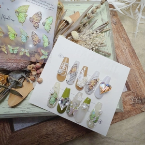 Detail of green embossed nail art stickers with butterfly and pearl accents