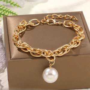 Close-up of golden chain bracelet featuring a large baroque pearl on a jewelry box