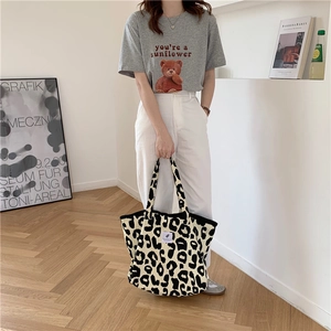 Detail of large leopard print canvas tote bag featuring a central white woven logo patch