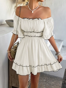 Detail of beige off-shoulder vacation dress featuring elegant black wavy ruffled edges