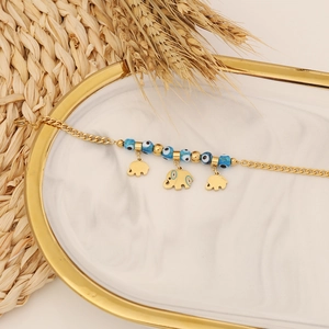 Golden elephant charm bracelet with blue evil eye beads on a marble display tray