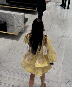 Detail of a floral print V-neck dress with layered cake skirt and vibrant yellow patterns