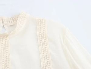 Detailed view of white chiffon top featuring elegant lace hollow patterns on the stand collar